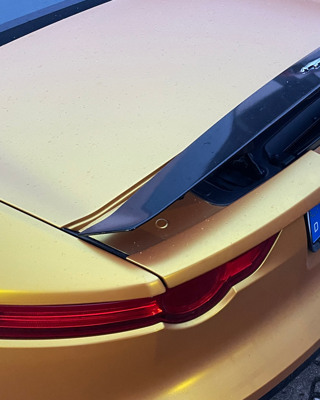 Detailaufnahme der Vollfolierung in Satin Gold am Heckspoiler und an der Kofferraumkante des Jaguar F-TYPE
